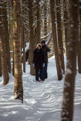 Ethnic couple snowshoeing in the forest near a waterfall