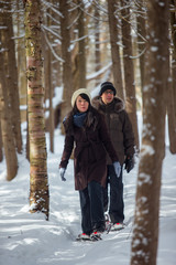 Fototapeta na wymiar Ethnic couple snowshoeing in the forest near a waterfall