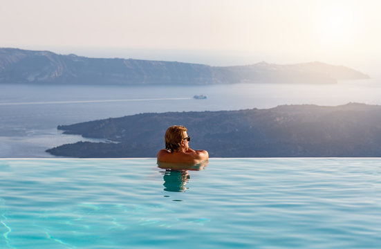 Mann genießt seinen Urlaub in einem Infinity Pool mit Sicht über das Meer