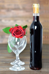 Valentines day wine and red rose. Red wine bottle, two glasses and red rose on wooden background
