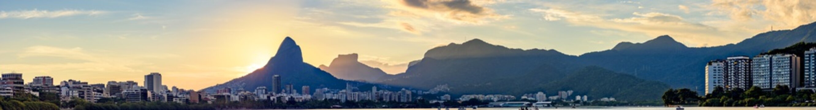 Panoramic image of the first summer sunset of the year 2018 seen from the lagoon Rodrigo de Freitas with the buildings of the city of Rio de Janeiro, hill Dois IrmÃ£os and Gavea stone