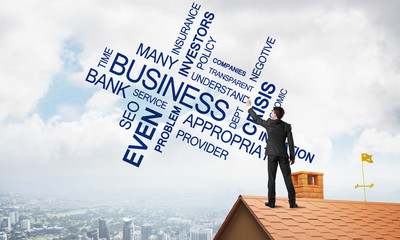 Young businessman standing on house roof and writing leadership skill concept. Mixed media