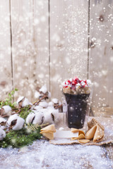 Obraz na płótnie Canvas A glass of coffee and marshmallow is poured over with syrup. cookies with traditional Christmas wishes. branch with cotton on a wooden background and falling snow