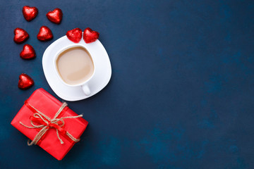 Obraz na płótnie Canvas Breakfast at Valentine's Day. Cup of coffee with heart shaped chocolates and gift box, flat lay with copy space