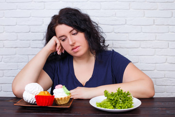 Young upset overweight woman bored of diets choosing between healthy and junk food. Dieting,...