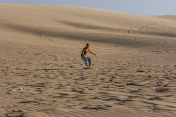 Young man sandboarding at sunset, Huacachina, Ica, Peru
