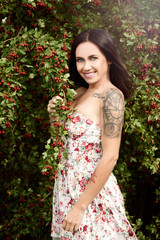 Beautiful girl is posing next to a rose hip. She is wearing a flower dress. Fashion photography.