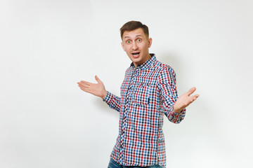 Handsome cheerful positive satisfied caucasian smiling fun young happy man 25-30 years in blue plaid shirt spreading hands on white background isolated, copy space for advertisement. Emotions concept.