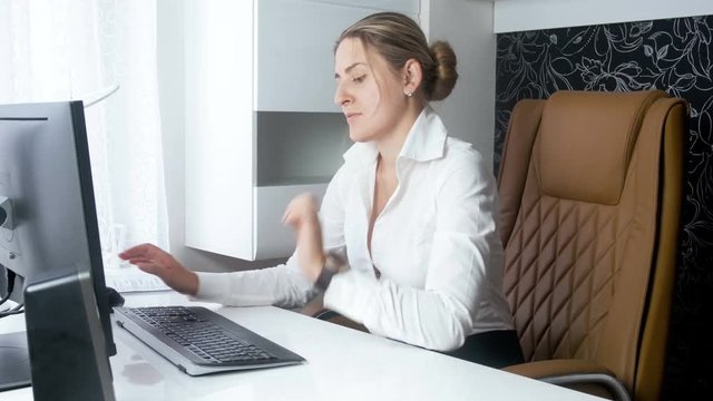 Beautiful sexy businesswoman sitting in big leather chair and using computer in office