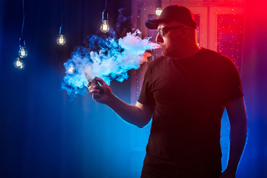smoking vape. Men with beard in sunglasses vaping and releases a cloud of vapor. A man smokes an electronic cigarette. Vape.