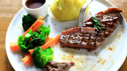 Premium quality Beef Steak set, medium rare grilled, slices on a fork  and the black pepper sauce on white plate, Potato or french fries and some vegetable salad as foods background, Australian Beef.