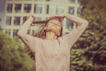 Beautiful young woman straightens hair in the park