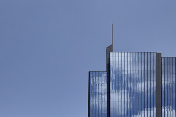 View of modern, glass building (skyscraper). Simple and modern composition with clear blue sky background.