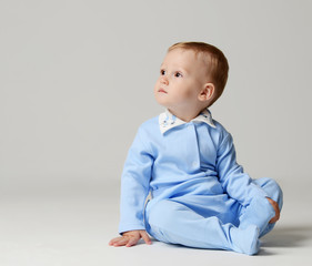 Infant child baby boy kid toddler sitting in light blue body cloth looking at the corner