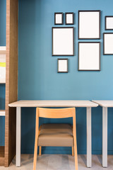 table and chair with blank photo frame on blue wall in class room or library