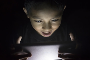 yound asian boy using digital tablet in dark
