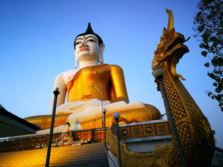Big Buddha statue in gold color on the back is blue sky evening