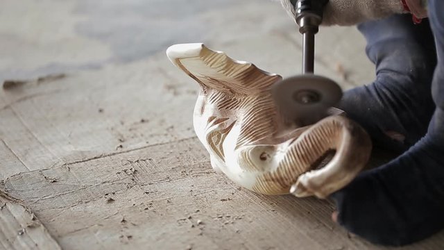 Traditional craftsman carving wood an elephant and sanding wood with motor sandpaper.