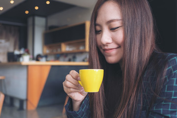 Closeup image of Asian woman smelling and drinking hot coffee with feeling good in cafe