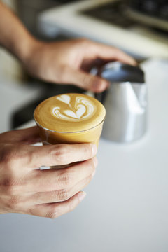 Hand holding cortado coffee in glass