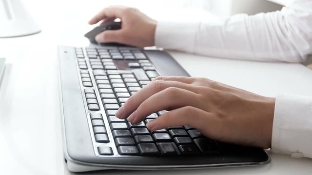 Closeup video of young businesswoman using computer mouse and typing on keyboard at office