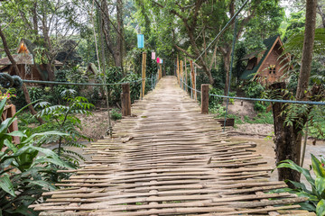 bamboo suspension bridge spanning the creek with house in the garden