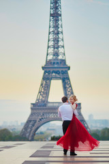 Couple dancing in front of the Eiffel tower in Paris, France - obrazy, fototapety, plakaty