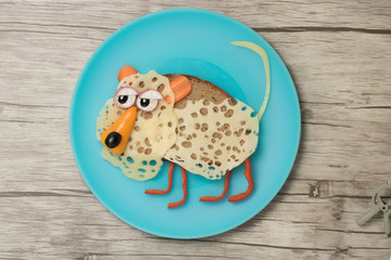 Obraz premium Leopard made with black bread, cheese and vegetables on plate and board