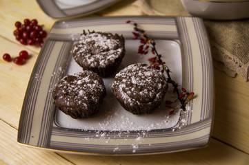 Three chocolate cupcakes with tea on a white tableware of a Christmas table