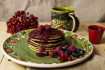 A pancake on the Christmas table with tea and raspberry jam