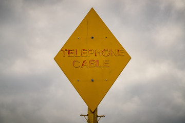Sign: Telephone cable with a cloudy sky in the background, seen in Grain, Kent, England, UK