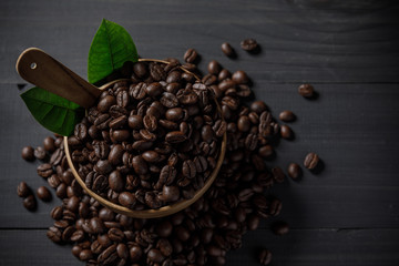 Coffee beans and coffee leaves in the bowl on the wooden table