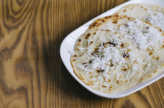 pancake with grated coconut topping in a plate on a white background. Malaysian delicacies
