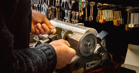 Close view of key copying machine with keys and locksmith hand - obrazy, fototapety, plakaty