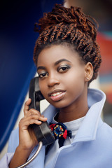 African girl with bright makeup and a smile holding the phone in the street close-up