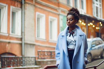 Stylish African girl in the blue coat on the street with bokeh in the background