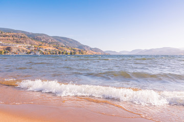 Waves crashing onto beach with mountains in distance on beautiful autumn day