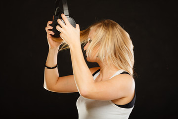 Blonde woman holding big headphones in studio