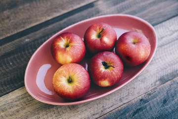red apple in a plate on a wooden table.fruit