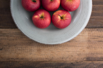 red apple in a plate on a wooden table.fruit
