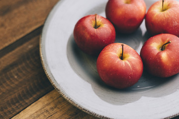 red apple in a plate on a wooden table.fruit