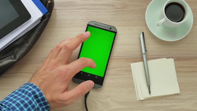 Man using a modern smartphone with green screen at her desk - green screen for placement of your own content