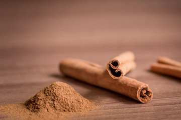 cinnamon sticks and powder on wooden table.