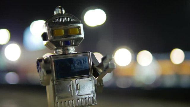 Old soviet robot walks around night city center with blur background bokeh close-up 4k