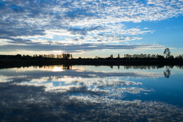 Morning scenery with clouds and sky reflecting surface.