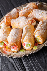 Delicious sweet rolls cannoli with cheese cream and candied fruit close-up. vertical