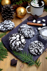 Chocolate crinkle cookies covered with sugar powder on a wooden board