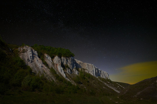 Night starry sky. View of the cliff in the moonlight.