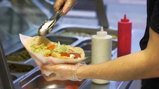 chef adding vegetables to pita at kebab shop