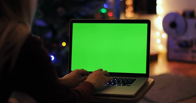 closeup top view woman using digital modern laptop green screen chroma key free content text application clicking cosiness relaxing Christmas tree New Year holiday social networking home interior